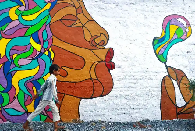 A boy walks past a painted wall.