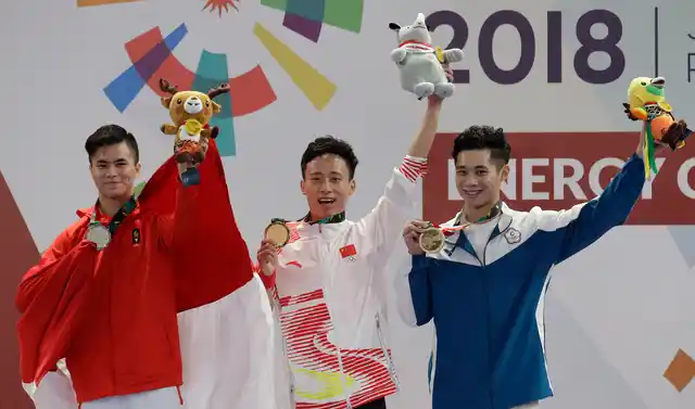 Gold medalist Peiyuan Sun of China, center, Silver medalist Edgar Marvelo of Indonesia, left, and Bronze medalist Tsemin Tai of Taiwan raise their medals during ceremonies for the Wushu men’s Changquan games at the 18th Asian Games in Jakarta, Indonesia on Sunday, Aug. 19, 2018.