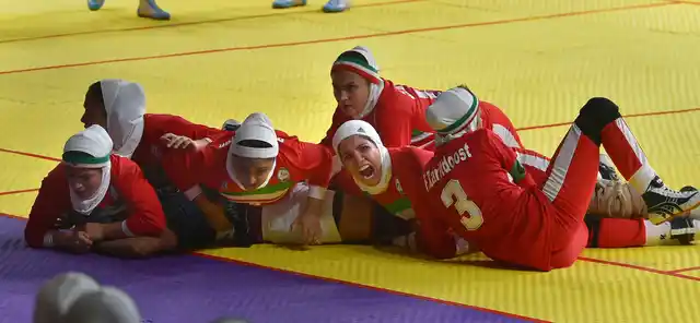 Iranian women’s kabaddi team members tackle down an Indian raider.