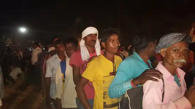 Farmers wait in a queue for dinner.