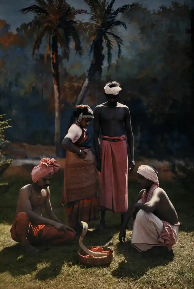 A group of people gather round and watch a snake charmer at work in India, 1923.