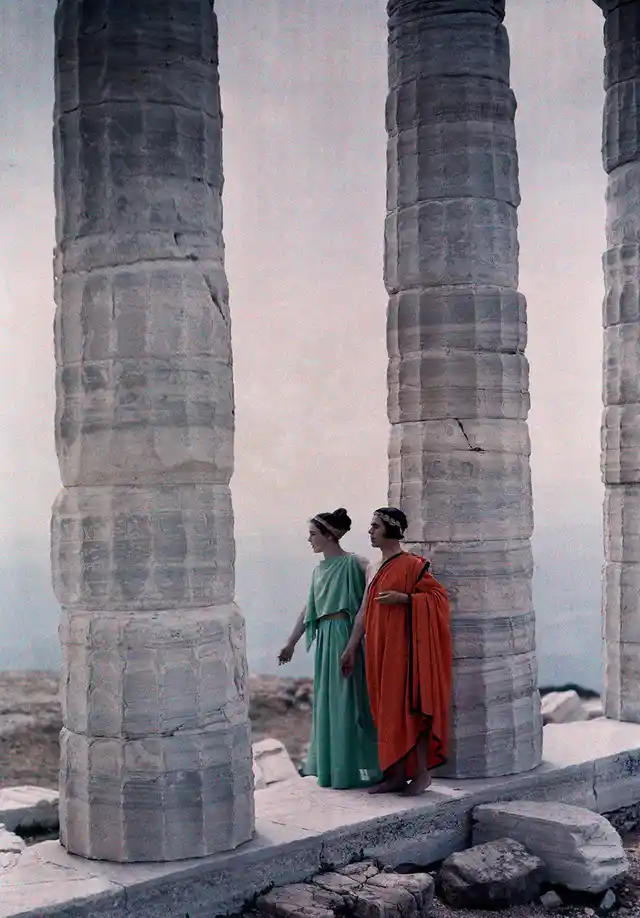 Two dancers in costume stand between the columns of Poseidon’s Temple, Greece, 1930.
