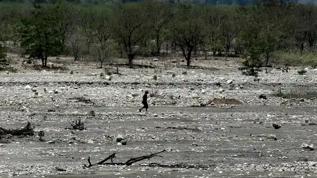 A man walks across a dry river bed in Fatukoko village in West Timor, Indonesia. The region is one of the driest parts of Indonesia, making farming difficult. Many villagers thus migrate to neighboring Malaysia in search of work.