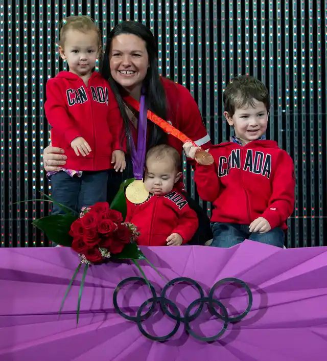 Canadian weightlifter Christine Girard poses with her children Aliana left, Samuel and Philip, right, and gold and bronze Olympic medals she was awarded during a ceremony in Ottawa.