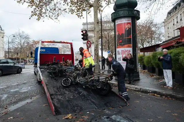 Workers clean up the street as they remove burned motorcycles, near the Arc de Triomphe in Paris.