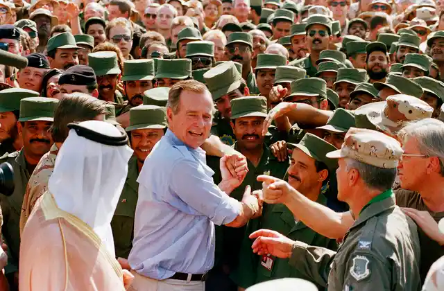 In this 1990 photo, President George HW Bush is greeted by Saudi troops and others as he arrives in Dhahran, Saudi Arabia, for a Thanksgiving visit.