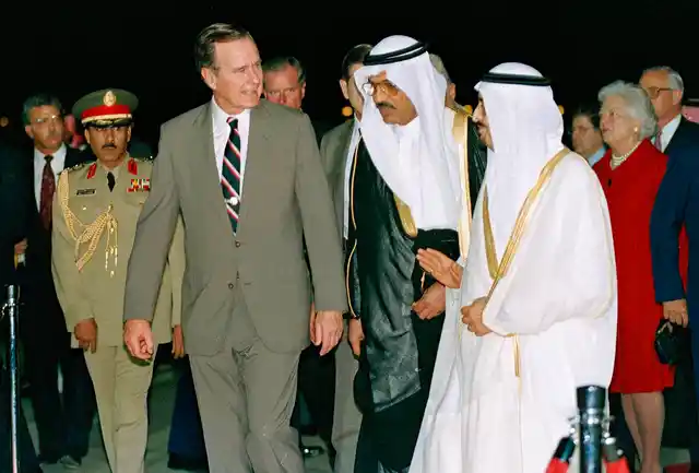In this 1990 photo, George HW Bush is greeted by King Fahd on his arrival in Jeddah, Saudi Arabia. At right is first lady Barbara Bush.
