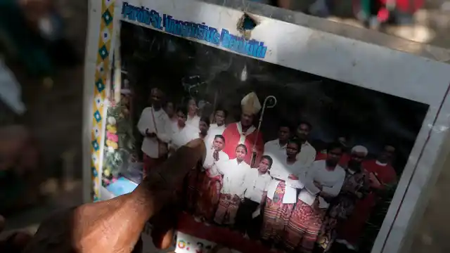 In this 23 October 2018 photo, Laurencius Kollo, great-uncle of Marselina Neonbota holds up a photograph taken in July 2009, which shows Marselina Neonbota, (third from left) posing with the district Bishop. 