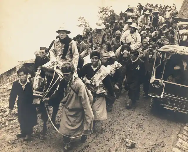 The Dalai Lama, in ceremonial dress, enters India through a high mountain pass. He is followed by the Panchen Lama. Sikkim, 1956
