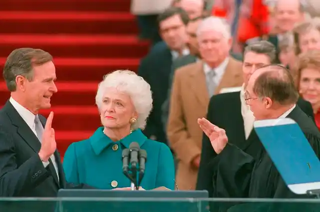 In this 1989 photo, President George HW Bush raises his right hand as he is sworn into office as the 41st president of the United States by Chief Justice William Rehnquist outside the west front of the Capitol as first lady Barbara Bush holds the bible for her husband. 