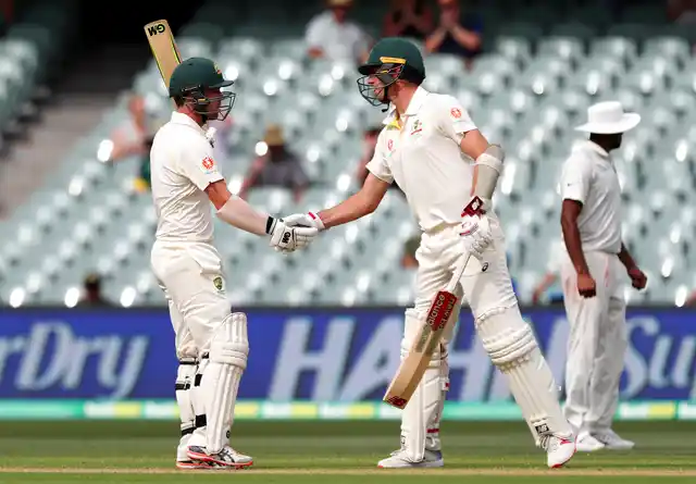 Australia’s Travis Head, left, is congratulated by teammate Pat Cummins after scoring a half century during the first cricket Test between Australia and India in Adelaide.