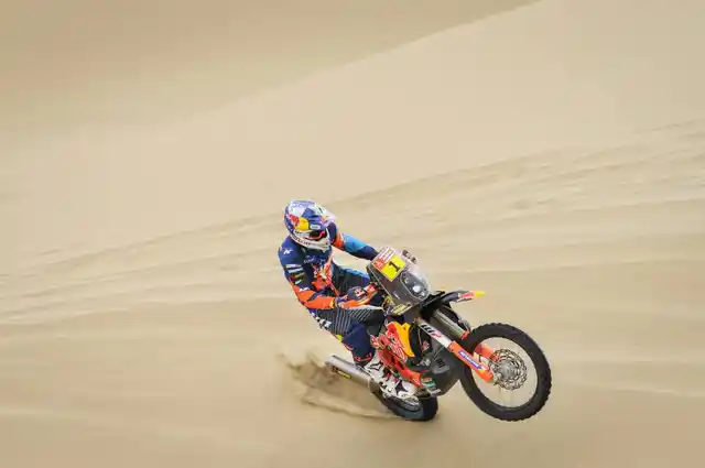 The front wheel of a bike pops as the rider tries to control through the sand.
