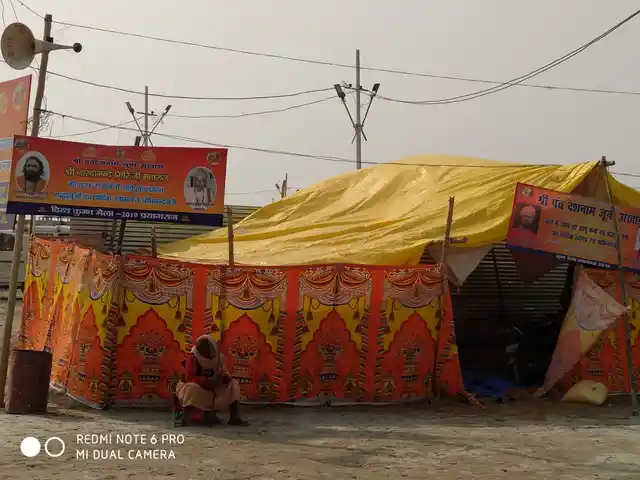 A man sitting adjacent to a makeshift shed. 