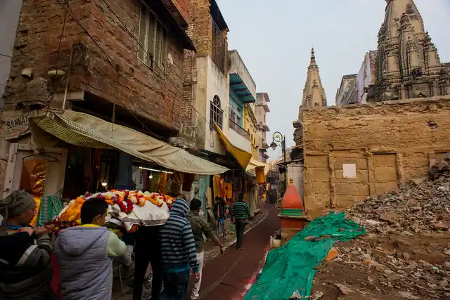 People carry a corpse to Manikarnika Ghat along a path at the demolition site.