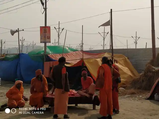 Men dressed in saffron clothes chat outside a makeshift tent.
