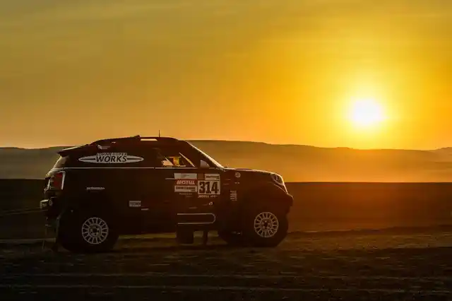 The sun sets over the desert of Pisco as an off road Mini driver passes by.