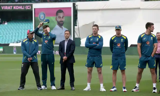 Australian team members stand by as India’s Virat Kohli accepts the winners trophy after play was called off on day 5 of their cricket test match in Sydney, Monday, Jan. 7, 2019. The match is a draw and India wins the series 2-1.