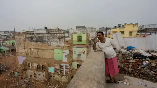 Jai Prakash Sharma leans on the parapet of the terrace of his house that he is about to vacate soon.