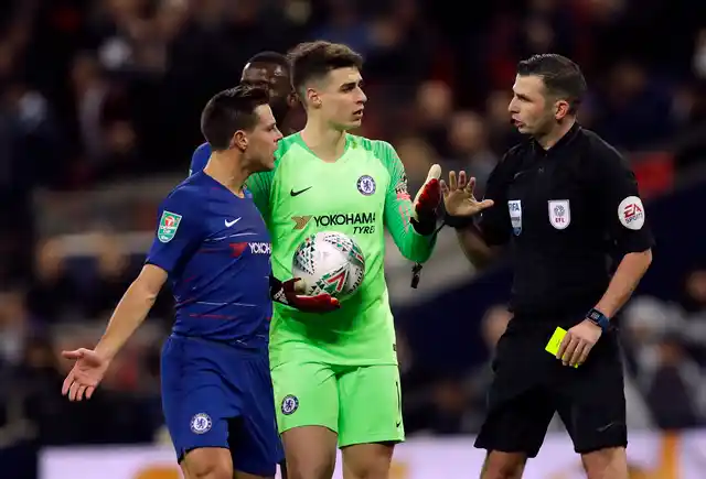 Chelsea’s Cesar Azpilicueta, left, argues as Referee Michael Oliver, right, gives a yellow card to Chelsea’s goalkeeper Kepa Arrizabalaga, after a video review.