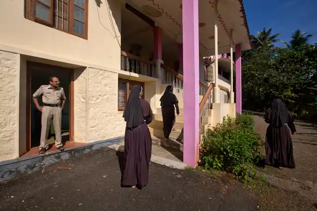In this Sunday, 4 November, 2018, photo, a policeman stands guard as nuns who have supported the accusation of rape against Bishop Franco Mulakkal return from the chapel in St. Francis Mission Home in Kuravilangad.
