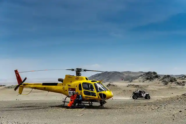 A rescue helicopter sits as a 4x4 is seen passing in the background.
