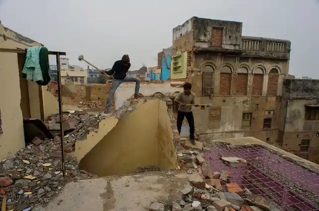Workers carry on demolition of a house at Lahori Tola in Varanasi.