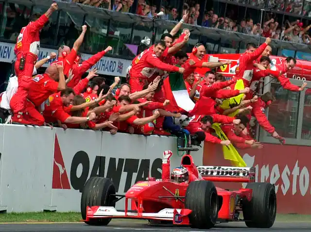 In this March 12, 2000, file photo, Ferrari’s F1 driver Michael Schumacher, of Germany, is cheered by his pit crew as he heads for the finish line to win the Australian Grand Prix auto race in Melbourne, Australia. 