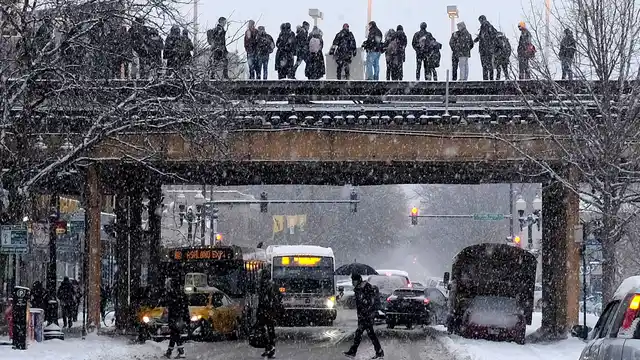 Commuters wait for a train as snow falls Monday, 28 January 2019, in Chicago. Wind chills could dip to negative 55 degrees in northern Illinois, which the National Weather Service calls “possibly life threatening.”
