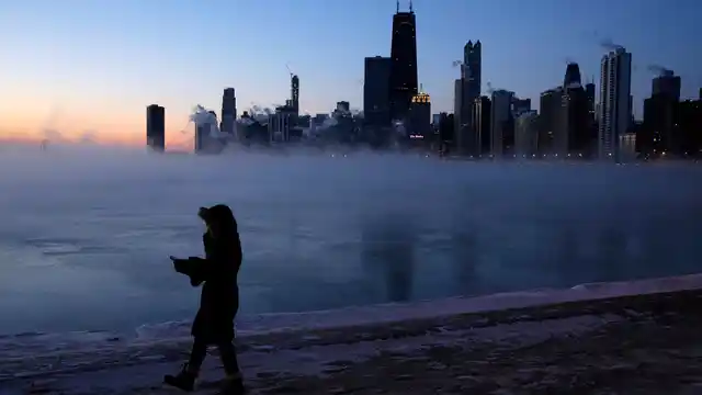 A person walks along the lakeshore, Wednesday, 30 January 2019, in Chicago. Widespread closures of schools and businesses has prompted the US Postal Service to take the rare step of suspending mail delivery to a wide swathe of the region.