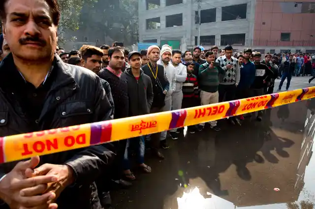 Onlookers gather after an early morning fire at a hotel killed at least 17 people in the Karol Bagh area of New Delhi. 