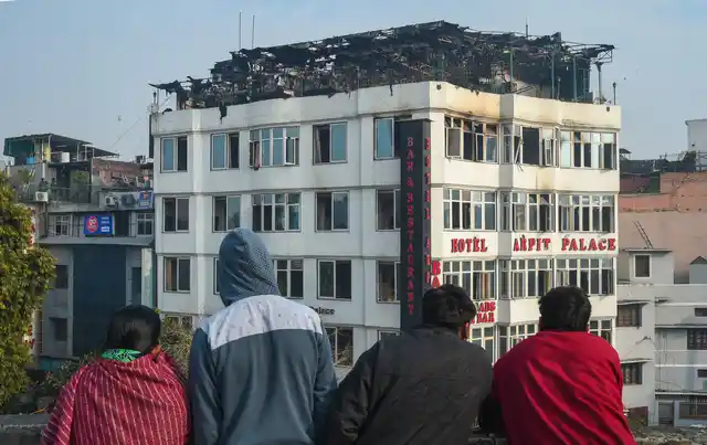 People look on at Karol Bagh’s Hotel Arpit Palace where a massive fire broke out, in New Delhi on Tuesday, 12 February. At least 17 people were killed and several others were injured in the accident.