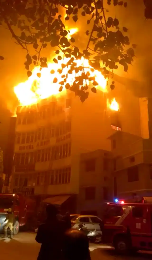 In this frame grab provided by Shyamal Duary, flames rise from a hotel that caught fire in the early hours of the morning in New Delhi on Tuesday. The fire engulfed a shoddily built budget hotel, killing 17 people and injuring at least four others, including a woman from Myanmar who leaped from an upper floor to escape the flames, officials told AP.