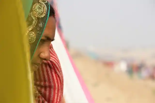 Natthi stares at the river, through the pile of clothes, left on bamboo shafts to dry,