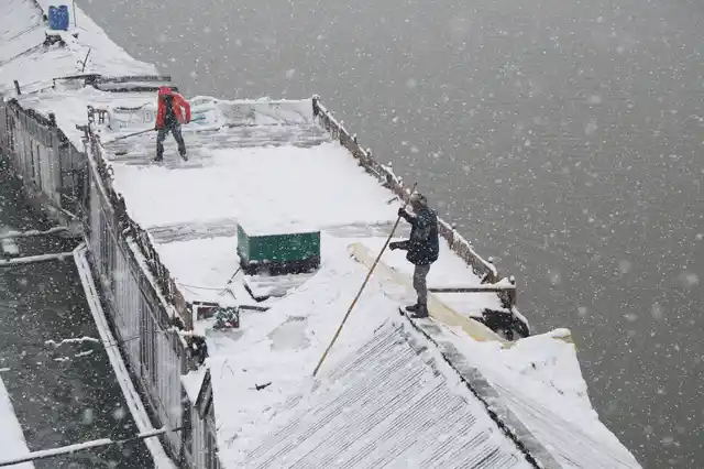 Boat men clear snow from their houseboat amid heavy snowfall in Srinagar. 