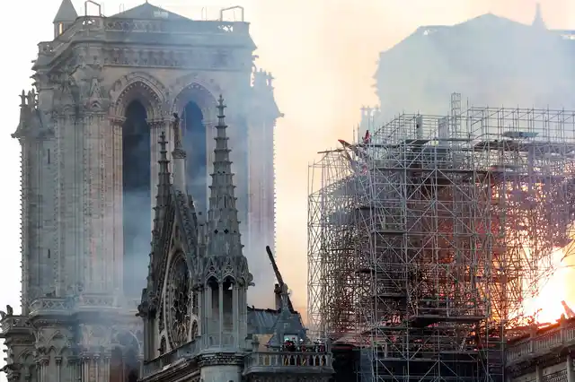 Massive plumes of yellow brown smoke is filling the air above Notre Dame Cathedral and ash is falling on tourists and others around the island that marks the center of Paris.