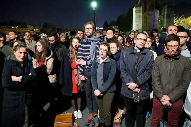 People pray as Notre Dame cathedral is burning in Paris, Monday, 15 April, 2019. 