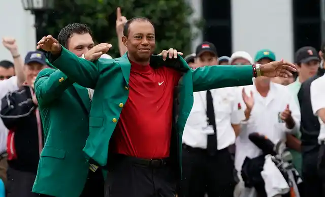 Patrick Reed helps Tiger Woods with his green jacket after Woods won the Masters golf tournament Sunday, April 14, 2019, in Augusta, Ga. 