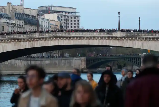 People watch as flames and smoke rise from Notre Dame cathedral as it burns in Paris.