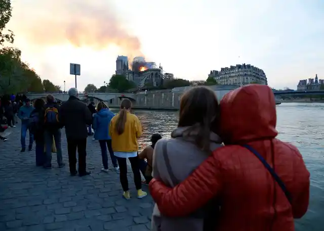People watch as flames and smoke rise from Notre Dame cathedral as it burns in Paris.