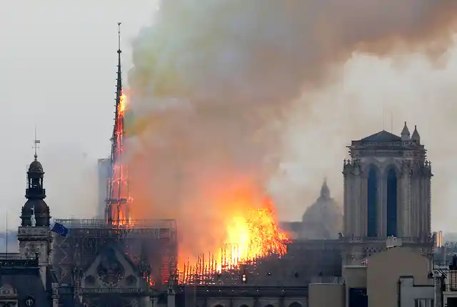 Massive plumes of yellow brown smoke is filling the air above Notre Dame Cathedral and ash is falling on tourists and others around the island that marks the center of Paris.