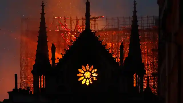 Flames and smoke rise from Notre Dame cathedral as it burns in Paris on 15 April, 2019. Massive plumes of yellow brown smoke is filling the air above Notre Dame Cathedral and ash is falling on tourists and others around the island that marks the center of Paris.