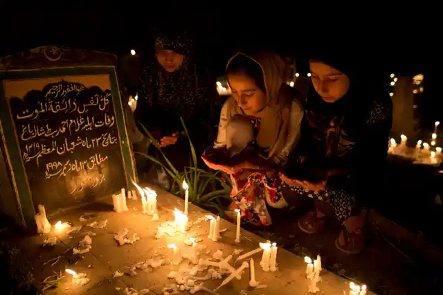 Kashmiri Shiite Muslim girls offer prayers at the candlelit graves of their relatives during Shab-e-Barat, on the outskirts of Srinagar.
