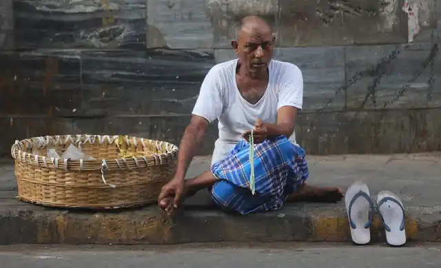 A Muslim labourer holds a prayer bead as he waits for a work on a pavement in Mumbai. 