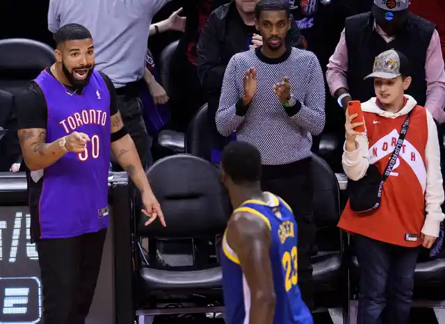 Rapper Drake, left, says something to Golden State Warriors forward Draymond Green (23) after the Toronto Raptors defeated the Warriors in Game 1 of basketball’s NBA Finals, Thursday, May 30, 2019, in Toronto. 