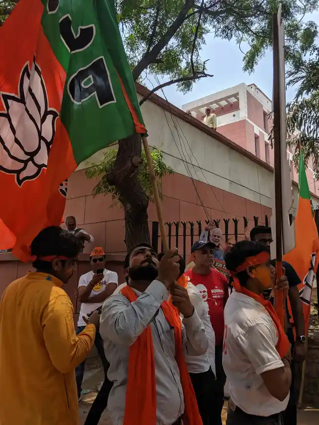 A BJP supporter hoists the BJP flag among other supporters