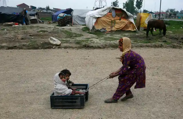 A Bakarwal nomad girl plays with her siblings at their temporary camp on the outskirts of Srinagar on Thursday, 2 May, 2019. Bakarwals are nomadic herders of Jammu and Kashmir who wander in search of good pastures for their cattle. 