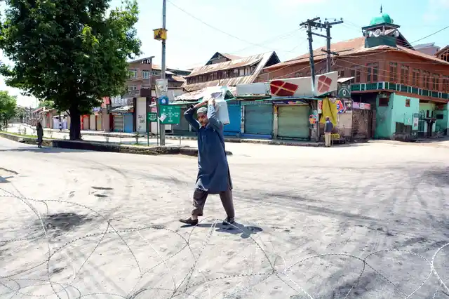 A milkman walks on a deserted road on the second day of curfew imposed to maintain law and order problem following the killing of most wanted militant and Commander-in-Chief of Ansar Gazwatul Hind Zakir Musa, in Srinagar. 