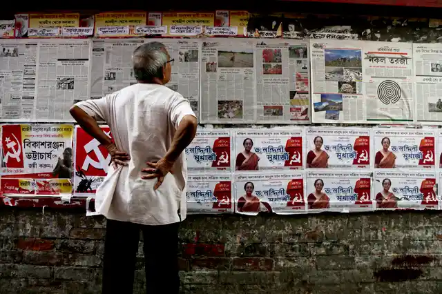 An elderly man reads the Communist Party of India-Marxist party newspaper pasted on a wall next to party candidate’s election posters in Kolkata.