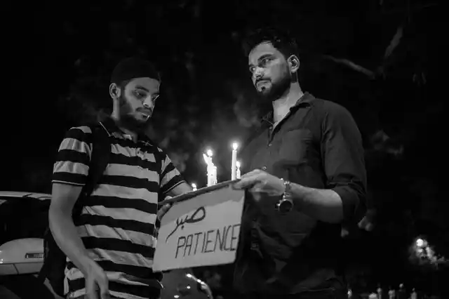 Two men hold candles and a placard reading ‘Patience’ at the Jantar Mantar protest on Wednesday. 