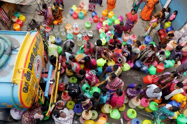 In this Wednesday, 19 June 2019, photo, people stand in queues to fill vessels filled with drinking water from a water tanker in Chennai. Millions of people are turning to water tank trucks in the state as house and hotel taps run dry in an acute water shortage caused by drying lakes and depleted groundwater.